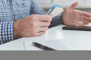 Belgeler ve Türk lirası banknotları tutan kişi – 2025 doçentlik başvurusu ücreti, evrak süreci ve ödeme yöntemleri.