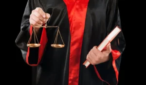 Yargı cübbesi giyen kişi elinde adalet terazisi ve kitap tutuyor – akademik etik ihlalleri ve doçentlik başvurularında hukuki süreç.