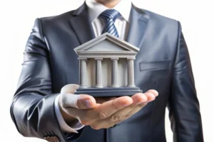 Takım elbiseli kişi elinde adliye biçiminde banka maketi tutuyor – kredi sözleşmeleri, dosya masrafları ve bankacılık hukuku danışmanlığı.