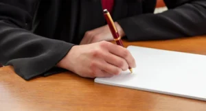 Cübbe giymiş akademisyenin doçentlik başvurusu için dilekçe yazması – jüri değerlendirmesi, puanlama ve yeniden başvuru süreciyle ilgili görsel.