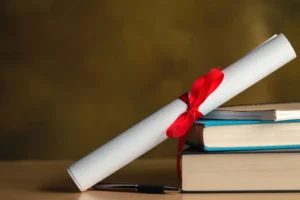 Kırmızı kurdeleyle bağlanmış bir diploma rulosu, yanında bir yığın hukuk kitabı ve bir kalemle akademik başarıyı ve hukuki eğitimi temsil eden görsel.