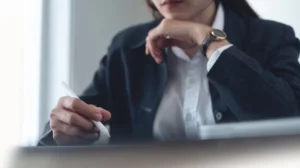 Profesyonel bir takım elbise giymiş bir hukukçunun veya danışmanın elinde stylus kalemle belge veya tableti incelediği, derinlemesine düşünce anını gösteren yakın çekim.