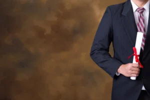 Takım elbiseli kişi elinde kırmızı kurdeleli diploma tutuyor – YÖK denklik başvurusu, belge süreci ve yurt dışı diploma geçerliliği.